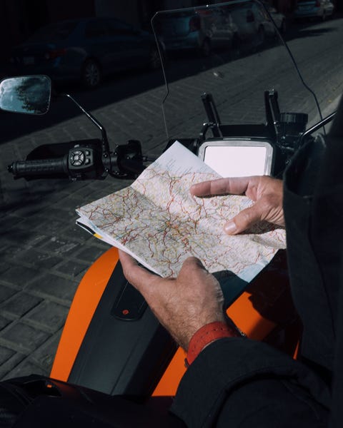 man holding a map next to motorcycle
